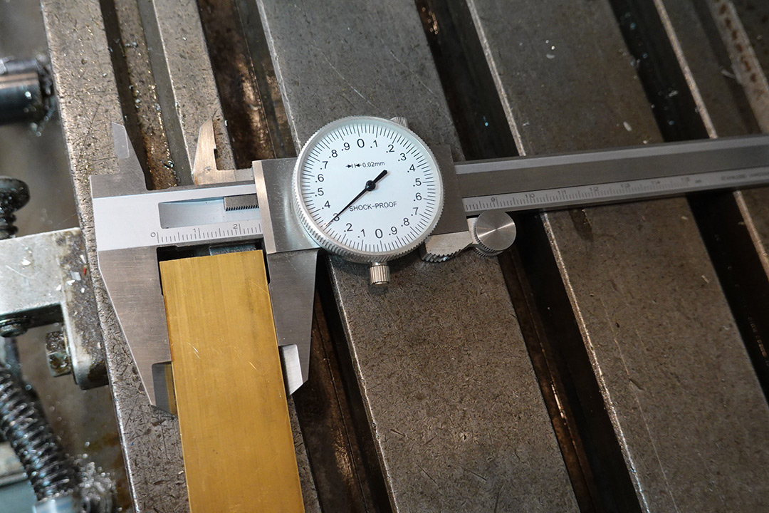 Calipers measure the width of the brass stock