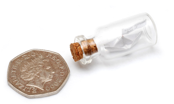 The paper ship in a bottle, with a 50p coin for scale