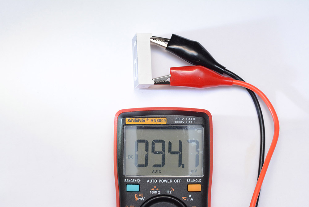 Multimeter connected to the pins of the display, reading 94.7mV