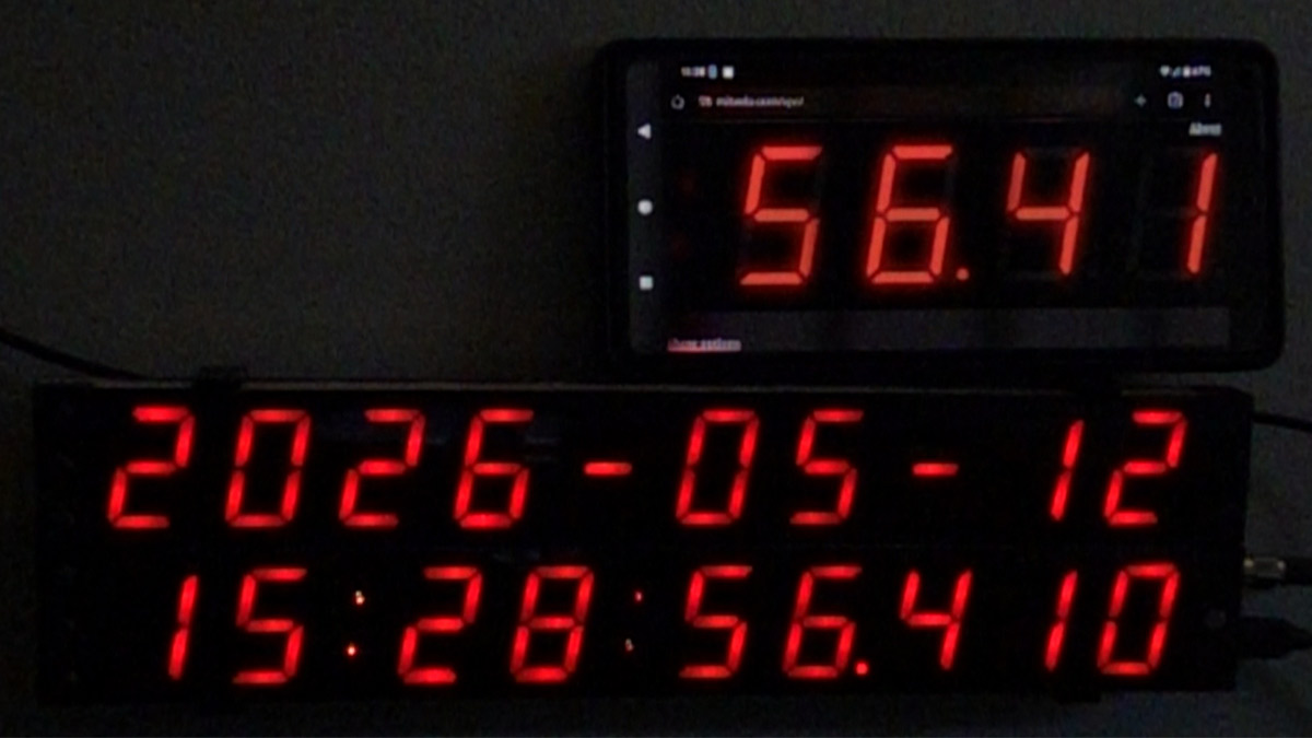Phone showing zoomed in section of VPC, perched on top of actual precision clock, time agrees