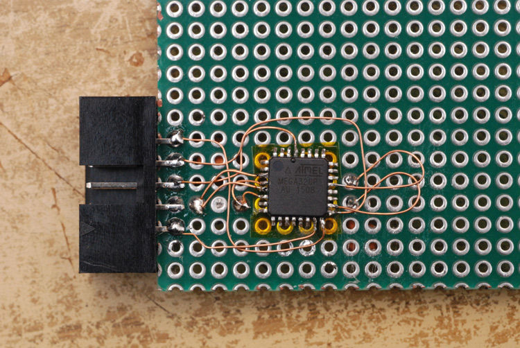 ATmega chip soldered onto protoboard with enamel wire and a header connector