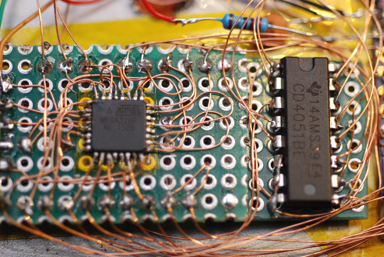 Closeup of the dense soldering of enamel wire around the atmega chip and multiplexer chip on protoboard