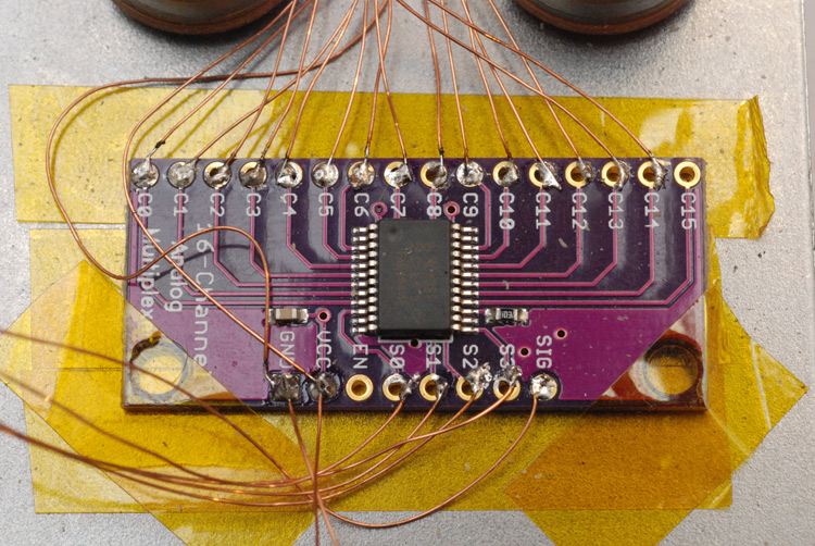Analog multiplexer breakout board with enamel wire soldered and kapton tape holding everything in place