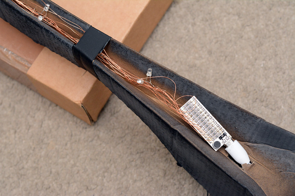 Many LEDs line the cardboard, wired up with magnet wire