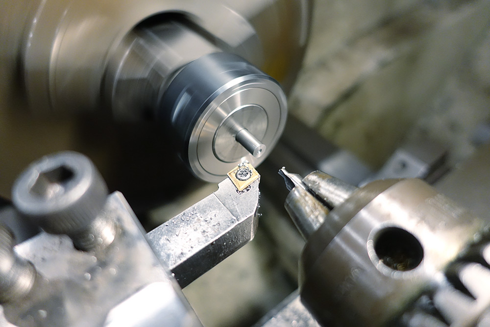 Steel held in a collet, facing the end and drilling a small divot for the tailstock