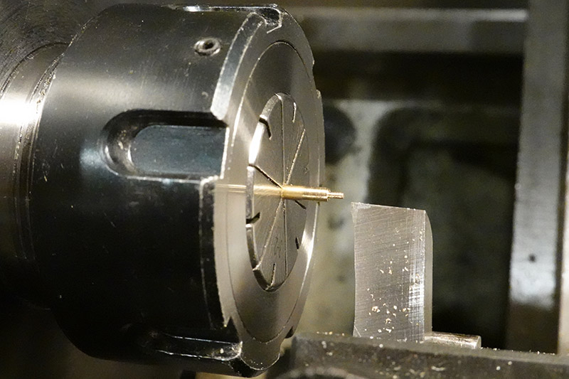 Tiny brass stock being held in a collet on the lathe, a shoulder is turned with a sharp cutting tool