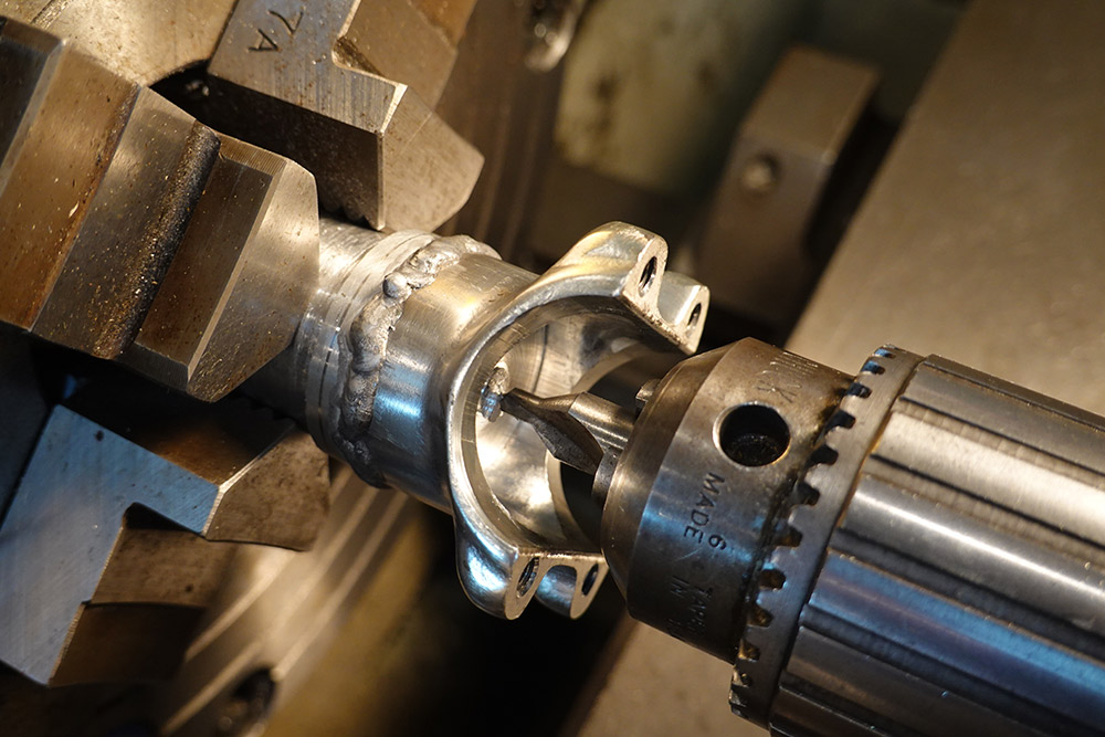 Welded part held in the four jaw chuck, with a centre drill in the tailstock approaching