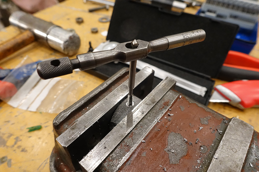 Tapping the holes with the steel ring in a vice. The tap wrench has 'england' written on the handle.