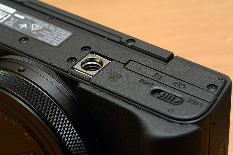 Underside of the Sony RX100 camera, with the tripod mount directly adjacent to the battery and SD card door