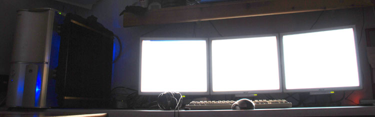View of the finished PC setup with headphones on the desk and monitors overexposed