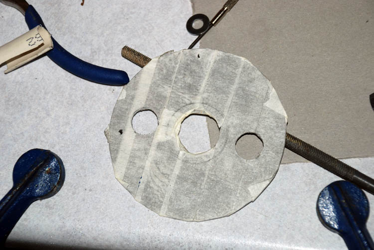 Hard drive platter covered in masking tape and holes drilled in it