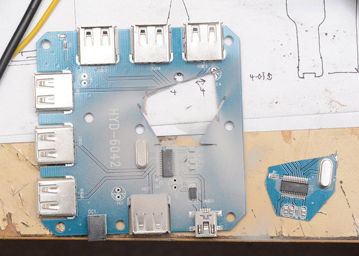 USB hub circuit board, with a section cut out of the middle with just a chip, some passives and a crystal on it