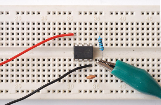 An ATtiny85, resistor, capacitor and crocodile clip on a breadboard